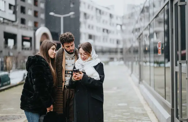 A dedicated team of young professionals is engaged in a mobile project discussion in a snowy urban setting, embodying teamwork and productivity outside the office.
