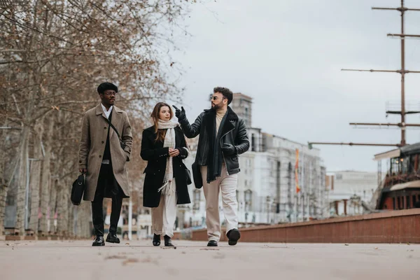 Three young business professionals engaging in a meeting while walking confidently through an urban city setting, embodying remote work dynamics.