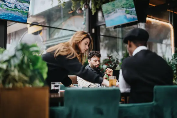 stock image Focused young business individuals collaborating on a project in the lively atmosphere of a contemporary city cafe.