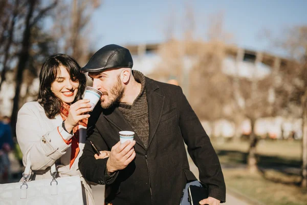 A professional man and woman take a sunny winter day break, sharing smiles and coffee, encapsulating work-life balance.