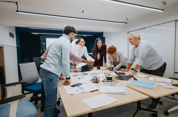 Diverse professionals attend a business lecture, collaborate, and brainstorm in a classroom. They discuss stats, share ideas, and improve their skills for successful teamwork and profit growth.
