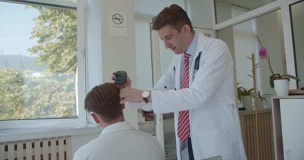 40年代的男性专家在现代临床实验室使用电视喉镜检查年轻患者耳聋和耳聋 — 图库视频影像