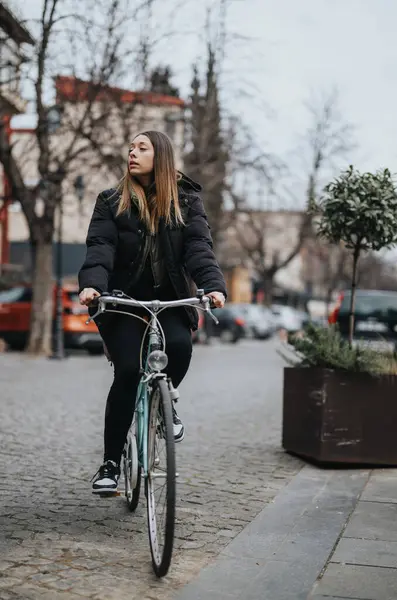 一位专注的年轻女性骑车人骑着她的老式自行车穿过城市街道 体现了城市生活方式和可持续交通 — 图库照片
