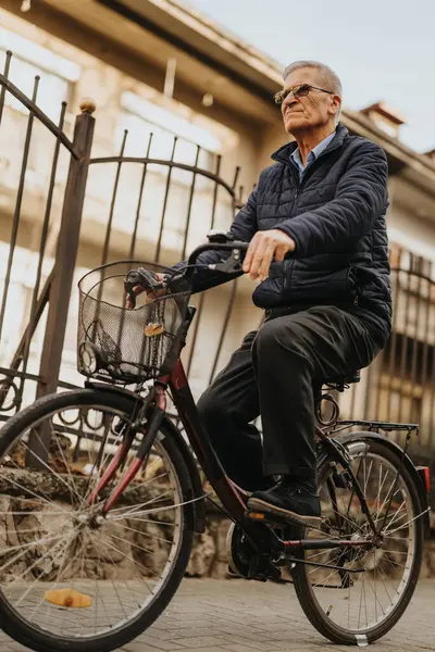 An elderly gentleman cycles through the city, exuding confidence and a healthy, active lifestyle in the golden years.
