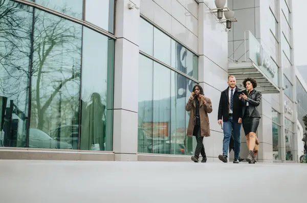 Three colleagues in business attire walking and talking in front of a modern office. Capturing diversity, teamwork, and urban professional life.