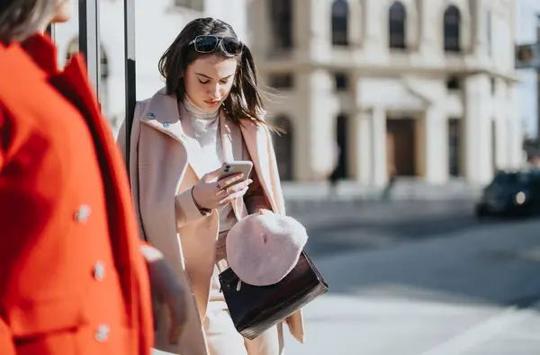 穿着时髦服装在城市街道上使用智能手机的年轻女商人 — 图库照片
