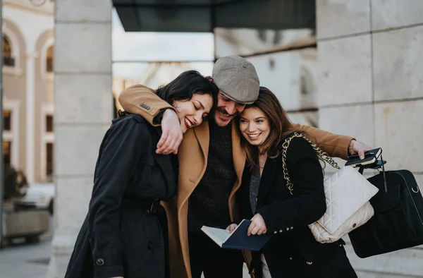A joyful trio of friends share a close moment, laughing and embracing on a city street, basking in each others company.