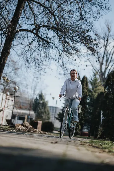 在和平的城市公园里 积极的女人在悠闲地骑自行车 — 图库照片