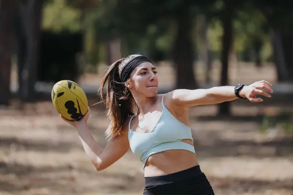 Athletic woman playing rugby in a sunny park, having fun and training outdoors. Active, happy, and fit.