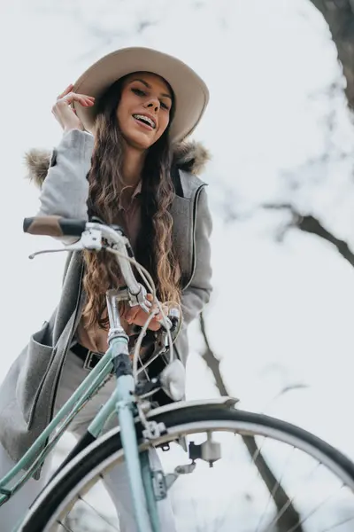 A fashionable young lady with a charming smile on a leisurely bike ride in urban scenery, radiating positivity and a carefree spirit.