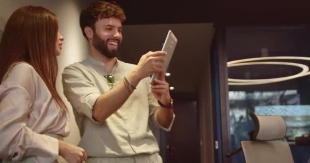 英俊的男性员工 在工作休息的时候用他的女同事的平板电脑拍照 他们正在放松 享受和享受工作的乐趣 — 图库视频影像