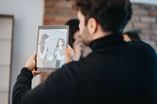 2人の女性の画像をキャプチャするタブレットを保持している人 — ストック写真