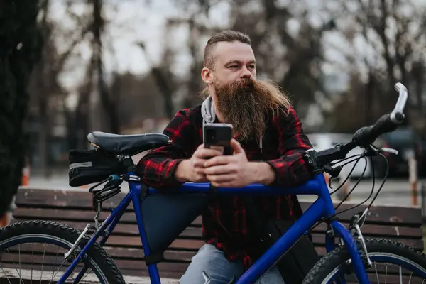 Stylový Vousatý Muž Chytrým Telefonem Odpočívající Modrém Kole Parku Předvádí — Stock fotografie