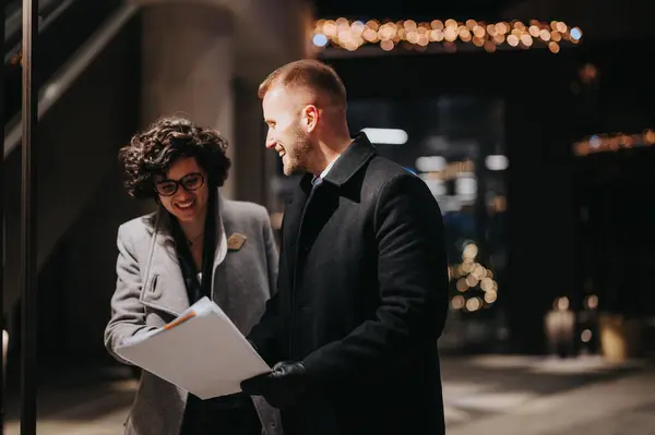 Business Couple Smiling Engaging Cheerful Discussion Documents Illuminated Building Night — Stock Photo, Image