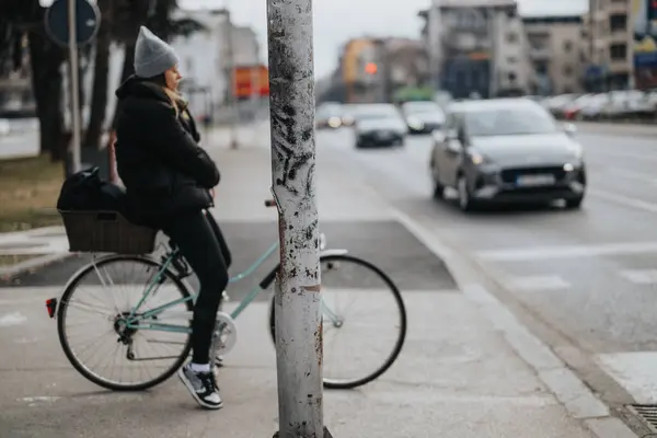 Женщина Велосипедистка Опирающаяся Столб Оживленном Городском Перекрестке Размышляет Городской Жизни — стоковое фото