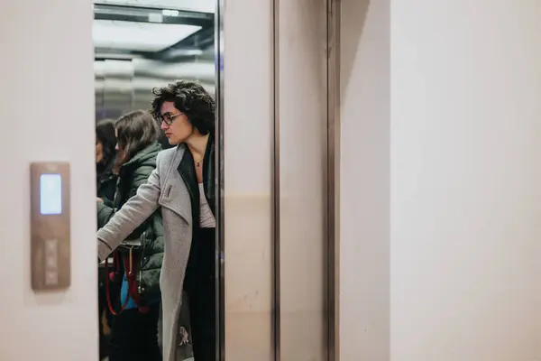 年轻女子走出电梯进入繁忙的城市环境 沉思着 — 图库照片
