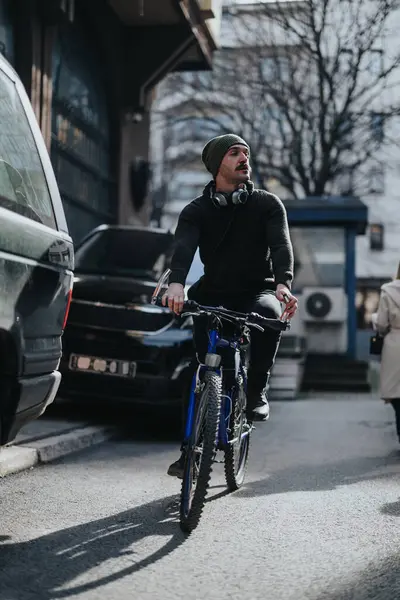Sıradan Giyinmiş Bereli Bir Adam Şehir Caddesinde Dağ Bisikleti Sürüyor — Stok fotoğraf