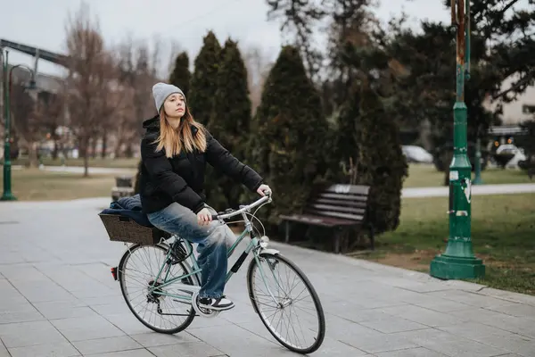 穿着冬衣 骑着老式自行车在公园里骑车的年轻女性 传递着一种自由感和积极的生活方式 — 图库照片