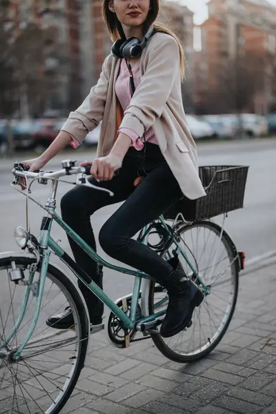 优雅的年轻女子在城市里骑着复古自行车 穿着夹克和耳机 体现了积极的生活方式和环保的交通 — 图库照片