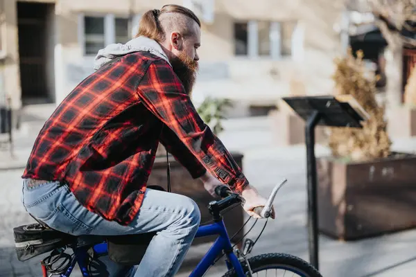 Hipster businessman on a blue bicycle in a city area, stopping to work on his smart phone remotely with urban lifestyle vibes.