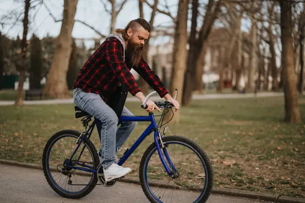 Casual Bebaarde Man Paardrijden Een Blauwe Mountainbike Een Parkpad Omgeven — Stockfoto