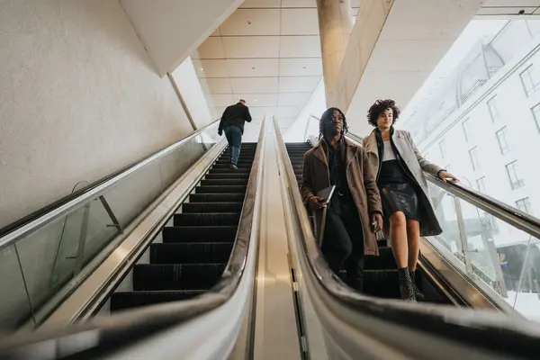 两名时尚专业人员乘坐扶梯 描绘了城市环境中的运动和城市生活 表现出一种冷静的当代氛围 — 图库照片