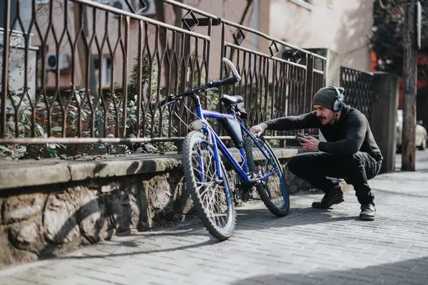 Kulaklıklı Güneşli Bir Caddede Bisikletini Tamir Etmeye Odaklanmış Bir Adam — Stok fotoğraf