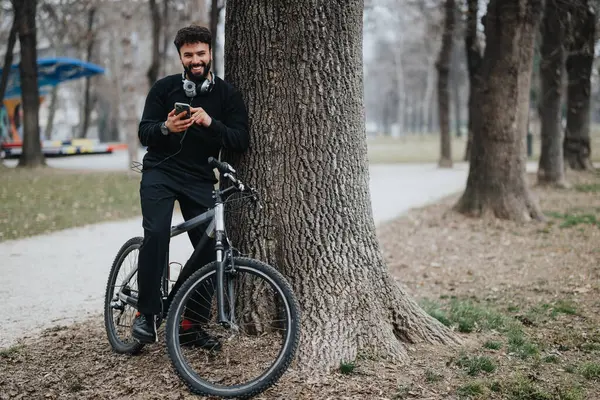 Улыбающийся Человек Велосипедом Парке Помощью Смартфона Наушников — стоковое фото