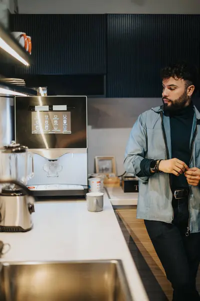 Sıradan Giyimli Genç Adam Çağdaş Bir Mutfak Düzeninde Otomatik Kahve — Stok fotoğraf