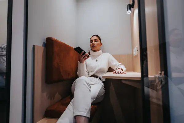 Businesswoman having video call meeting while sitting in soundproof phone booth at the office.