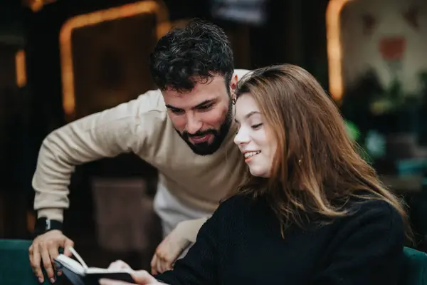 一个快乐的男人和一个女人在一个温馨的室内空间里看笔记本的同时 还在随意地谈论生意 — 图库照片