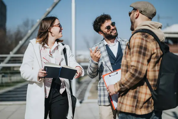 Three young professionals engage in a business meeting outdoors, discussing strategies and sales in a downtown city area.