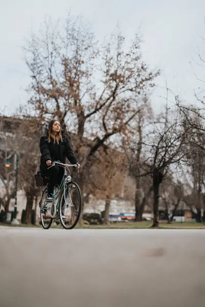 一个光秃秃的女人骑着自行车穿过一座城市公园 — 图库照片