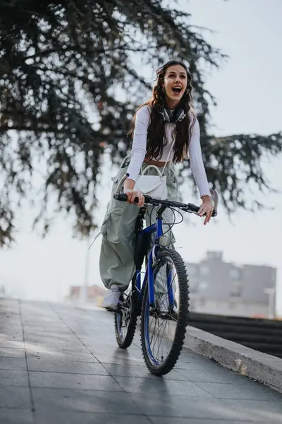 在阳光灿烂的一天 快乐的年轻人骑着自行车 脖子上挂着耳机 表达着喜悦和自由 — 图库照片