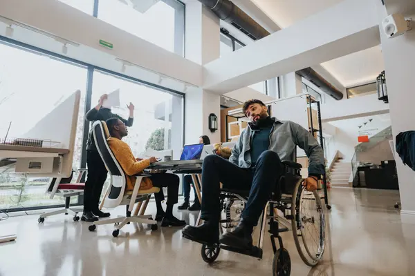 車椅子の人を含む多様な同僚と連携し 明るいオフィススペースでコラボレーションする — ストック写真