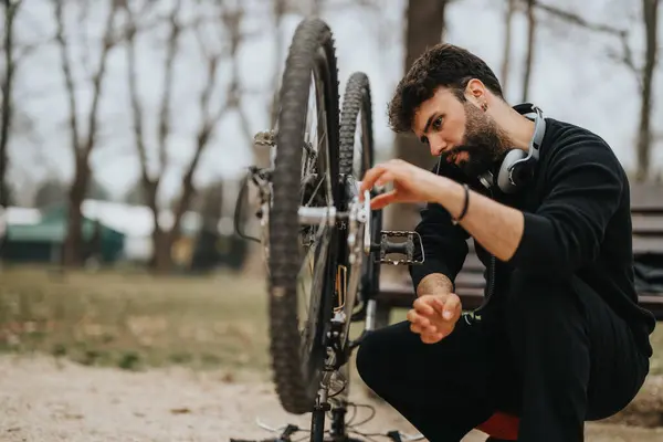 静かな都市公園で屋外で彼のマウンテンバイクを修理し 維持するために休暇を取る集中した起業家 — ストック写真