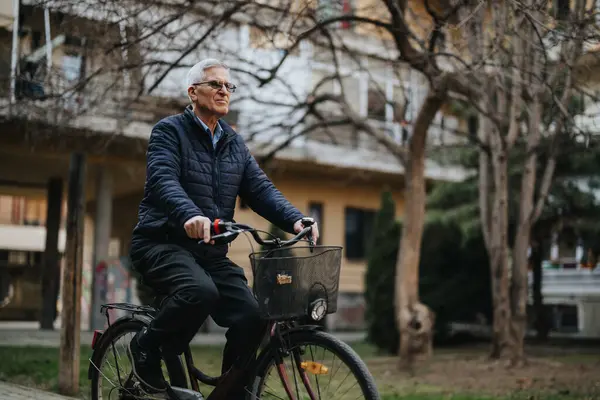 Active elderly gentleman cycling outdoors, showcasing a healthy lifestyle and leisure activity for seniors in an urban park setting.