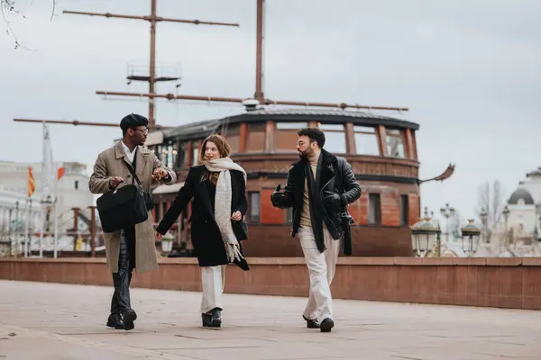 Three young business professionals engage in an informal meeting outdoors, walking together in an urban setting, exuding teamwork and collaboration.