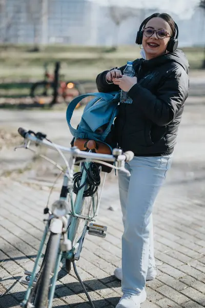 城市骑自行车时 手持耳机 手持水瓶的活跃女性 — 图库照片