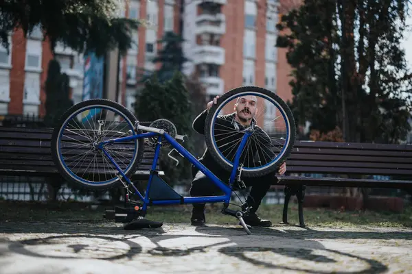 Şehir Parkı Dekorasyonuyla Bisiklet Tekerleğini Tamir Etmeye Odaklanmış Adam Günlük — Stok fotoğraf