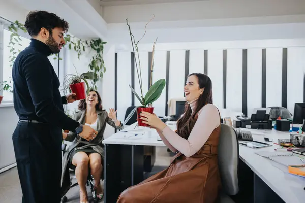 In a brightly lit office, co-workers are exchanging potted plants, sharing laughter and fostering a positive work environment.