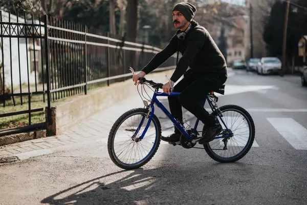 Şık Bir Genç Adam Kulaklıklarla Canlı Mavi Bir Dağ Bisikletinin — Stok fotoğraf