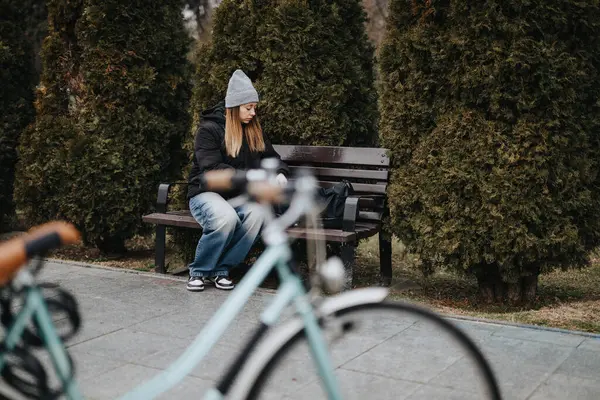 Reflekterande Ung Kvinna Sitter Ensam Parkbänk Hösten Med Suddig Cykel — Stockfoto