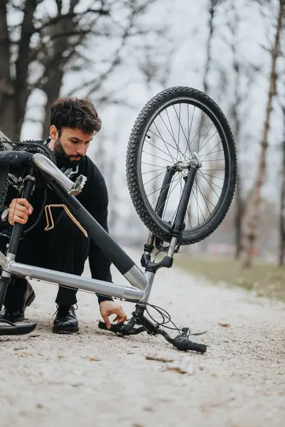 A business entrepreneur takes a break to repair his bike tire outdoors, showcasing multitasking and problem-solving skills.
