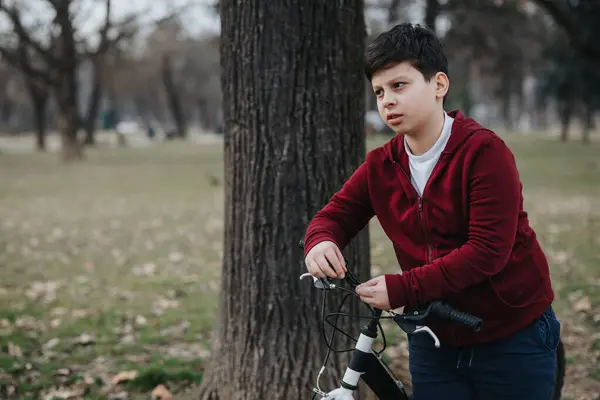 一个活泼的小男孩在茂密的公园里悠闲自在地骑自行车 表现出欢乐和青春的活力 — 图库照片