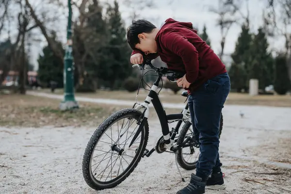 一个活泼的小男孩在风景秀丽的公园里骑自行车时停下了脚步 这反映出一种快乐和自由的感觉 — 图库照片