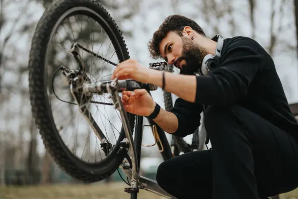 Focused businessman doing bicycle maintenance outdoors, demonstrating multitasking and a proactive attitude.