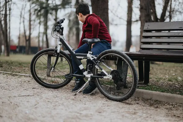一个年轻人躺在公园的长椅上 身边拿着自行车 在户外享受着片刻的宁静 — 图库照片