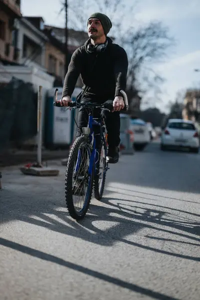 城市环境中以骑自行车为主 身穿休闲装 头戴耳机 描绘了积极的城市生活方式 — 图库照片