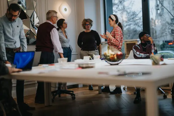 A team of business coworkers engage in a discussion at a well-lit office space, embodying teamwork and collaboration in a casual work environment.